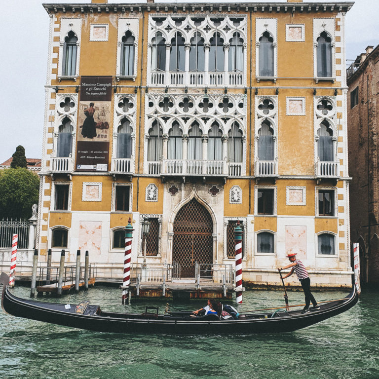Beautiful old building in Venice, with a gondola in front of it. Seen from the water.