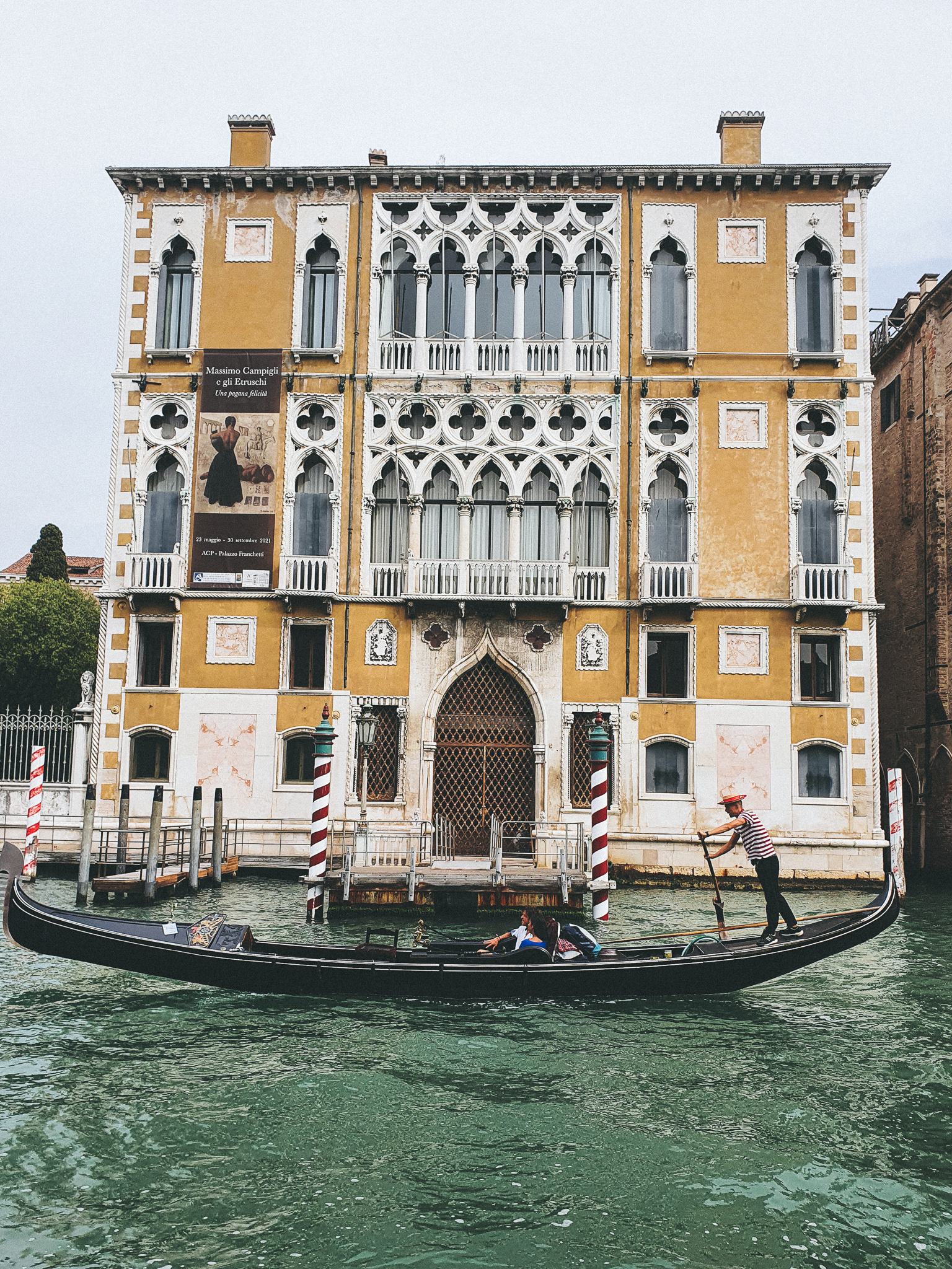 Beautiful old building in Venice, with a gondola in front of it. Seen from the water.